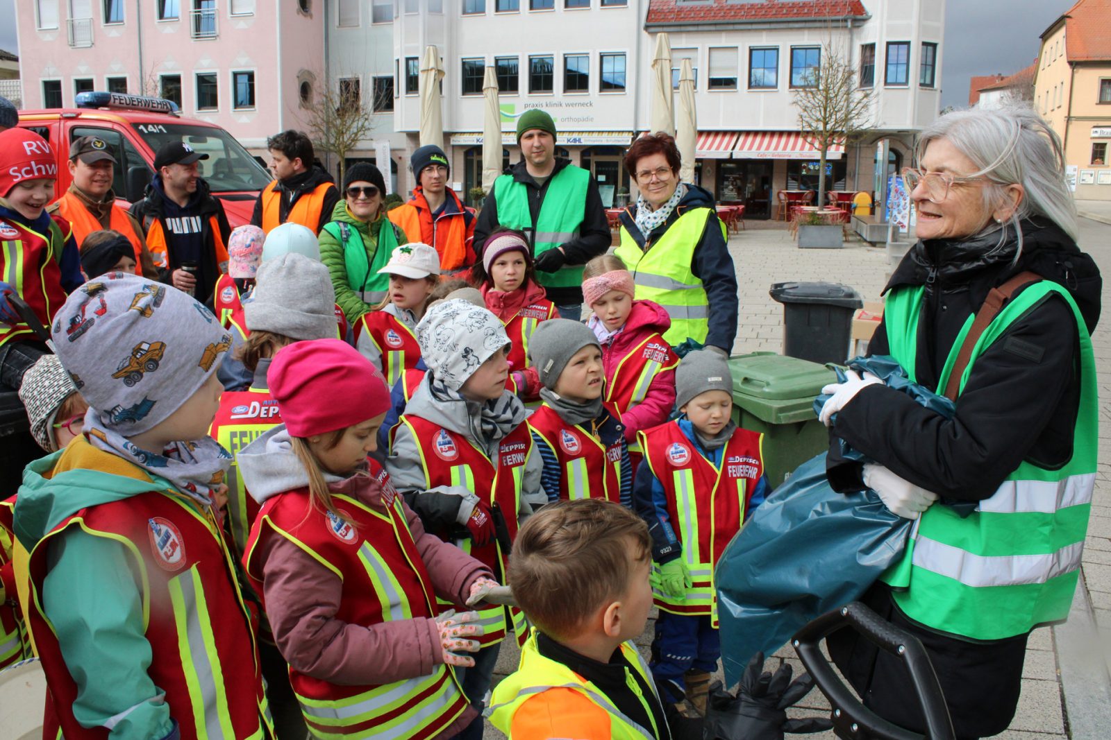 Roswitha Ziegler mit einem Müllsack im Gespräch mit Kindern der Kinderfeuerwehr in Warnwesten